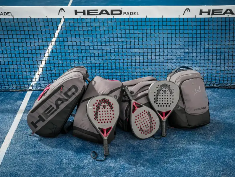 HEAD Padel Schlaeger und Taschen auf einem blauen Padelcourt vor dem Netz mit HEAD Padel Werbebanner - HEAD Padel Kollektion bei Padel4Players