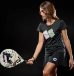 Royal Padel 36 Aniversario Light Lifestyle Frau von der Seite schwarzer Hintergrund Schlaeger am Koerper buntes Aniversario-Design sichtbar