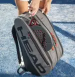 Head Coello Tour Padel Bag L Lifestyle Person traegt Tasche als Rucksack von hinten auf Padelanlage mit Padelschlaeger oben