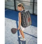 Head Coello Tour Padel Bag L Lifestyle junges Maedchen auf Padelcourt traegt Tasche als Rucksack HEAD Schriftzug auf grauem Hintergrund