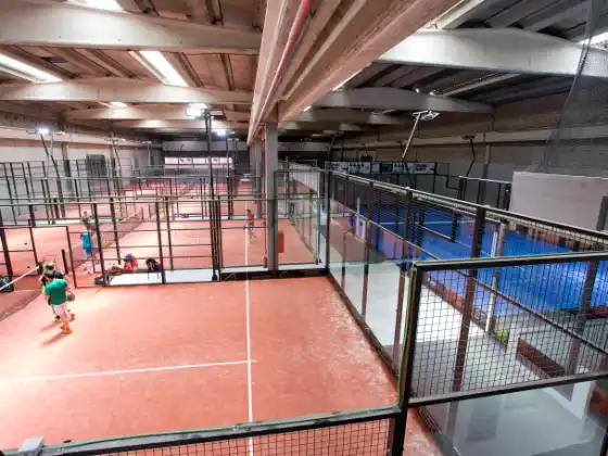 Indoor-Padelhalle mit mehreren MS Manza Plätzen in rotem Kunstrasen mit Spielszene