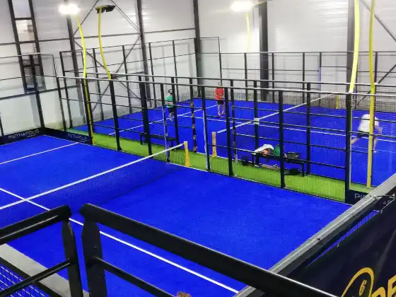 MS Manza Indoor-Padelplätze im Pietramolis-Center mit gelben Säulen und blauem Kunstrasen