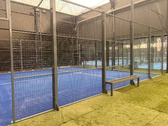 MS Manza Indoor-Padelplatz mit grauer Stahlkonstruktion und Sitzbank in Vereinsanlage