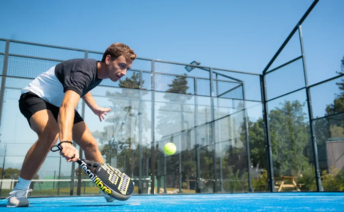 Padelspieler beim Padel allein trainieren mit tiefem Defensiv-Schlag und gelbem Ball