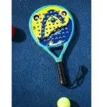 Head Monster Kids Padelschlaeger auf blauem Padelcourt von oben mit Padelball daneben tuerkis-gelbgruenes Monster-Design