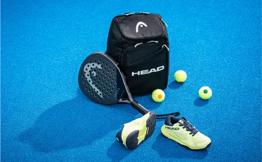 Padeltasche mit Padelschläger, Padelschuhen und Padelbällen auf dem blauen Court