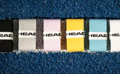 Sechs HEAD Padel Overgrips in verschiedenen Farben auf blauem Padel-Court – Uebersicht der Griffband-Auswahl