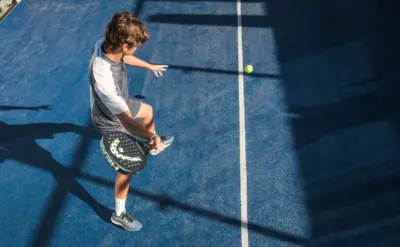 Padel-Spieler auf blauem Court von oben fotografiert nach einem Vibora-Angriffschlag mit fliegendem Ball