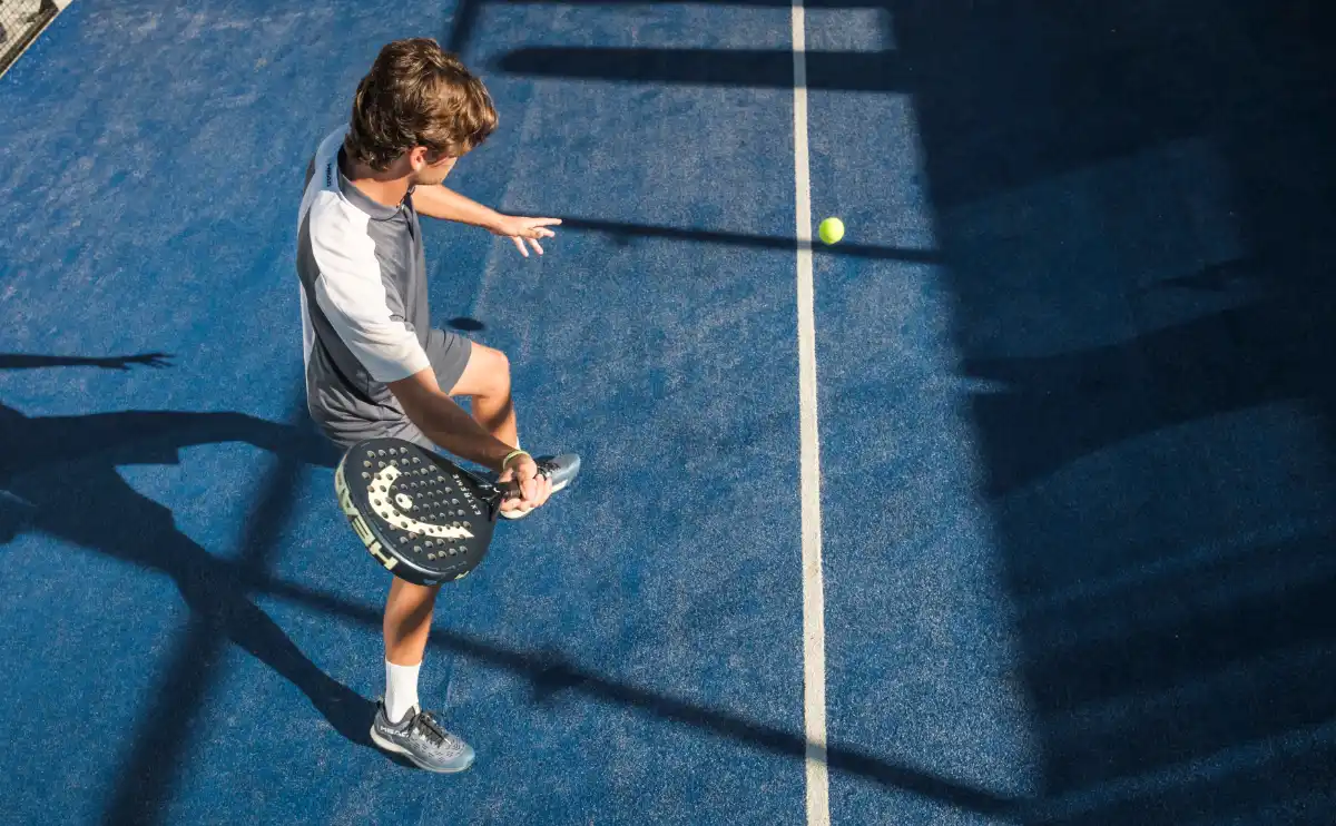 Padel-Spieler auf blauem Court von oben fotografiert nach einem Vibora-Angriffschlag mit fliegendem Ball